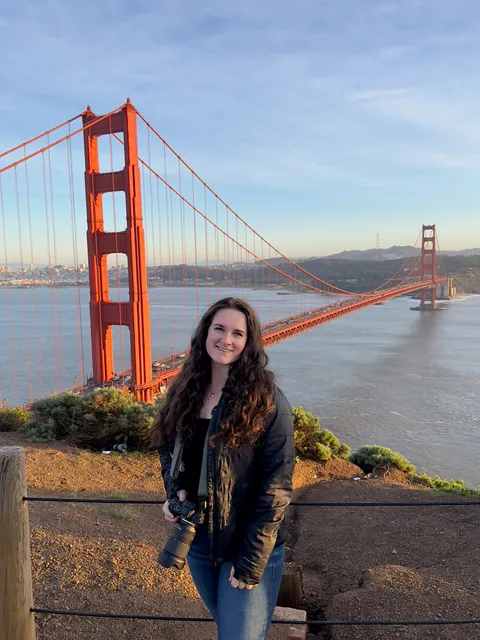 Marin with a camera in front of the Golden Gate Bridge