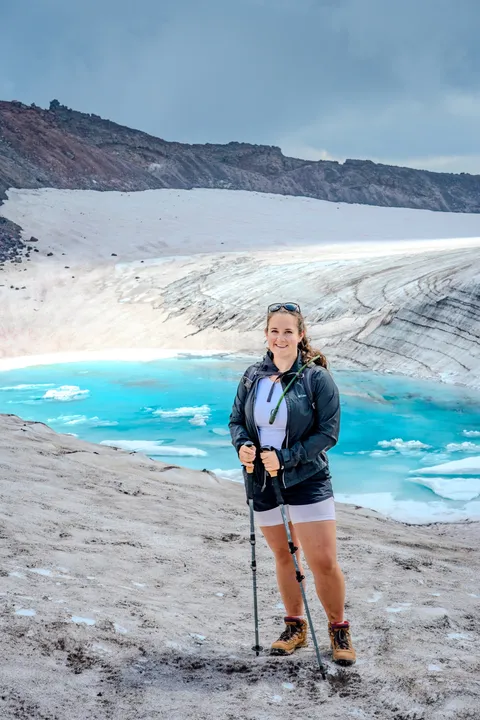 Marin on a Cascades summit above a turquoise glacial lake